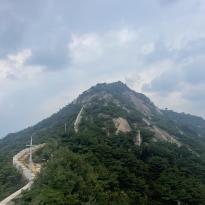 Image of mountain peak with trail and fortress wall 