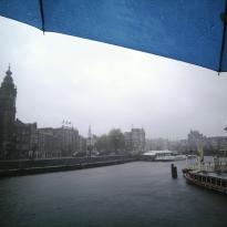 Amsterdam on a rainy morning, with the edges of a blue umbrella visible from the top-right corner and top edge.