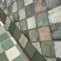 An up-close shot of green- and brown- colored tiles atop the roof of a church.