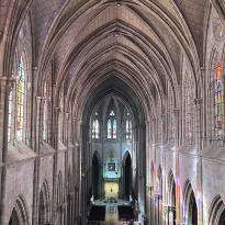 The interior of the Basílica del Voto Nacional. Arched ceiling with large stained glass windows.