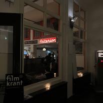 A cozy, dimly lit bar with a red neon sign that reads 'Kriterion.'