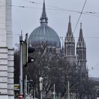 A photo of Vienna's Maria vom Siege, with gray skies and the city's architecture in the surrounding environment.