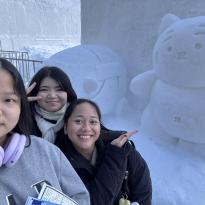My friends and I taking a selfie in front of a cute tiger snow sculpture at the Sapporo Snow Festival