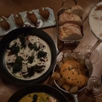 4 vegan croquettes next to a mini aluminum tray filled with bread. Below the croquettes is a dish composed of roasted beetroot in a cashew cream sauce along with patatas bravas in a tin pan. 