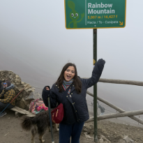 Me in front of the Rainbow Mountain sign!