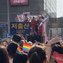 An image of the Seoul Queer Culture Festival crowd witch performers dancing on top of a moving float.