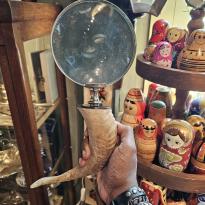 The author is holding a magnifying glass by its handle in front of him displaying the craftmanship of an animal tusk used as its handle.