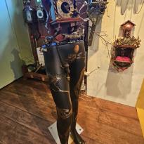 A clock carved into the top of the torso of a gold and black mannequin 