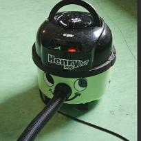 A mint green vacuum shaped like a pot with a black bowler hat with the hose for the nose. 