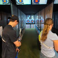 Writer practicing archery in an archery lesson. 