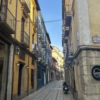 A narrow story street with two yellow buildings on either side.