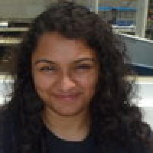 Smiling woman with curly hair outdoors. This alt text was added with Al; accuracy may vary.