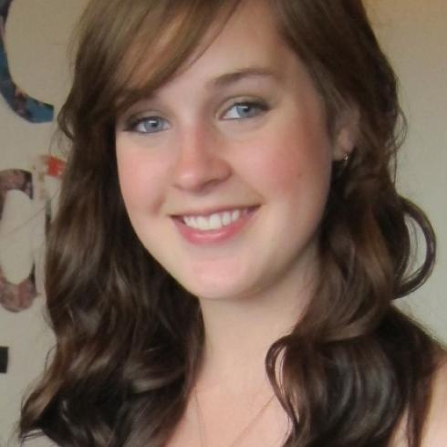 Smiling woman with long hair in a softly lit room. This alt text was added with Al; accuracy may vary.