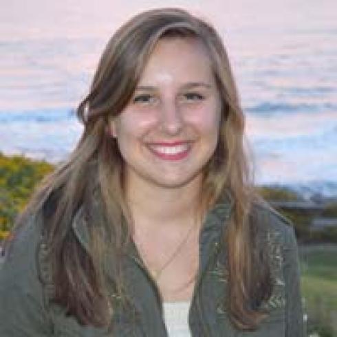 Smiling woman with headscarf in front of wheat backdrop. This alt text was added with Al; accuracy may vary.