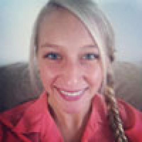 Smiling person with blonde hair braided, wearing a red shirt. This alt text was added with Al; accuracy may vary.