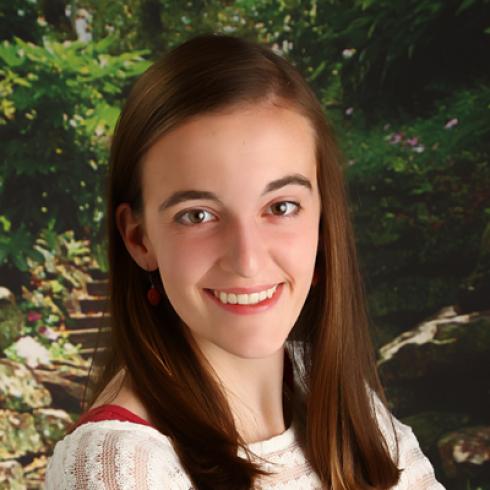 Smiling woman in denim jacket against gray background. This alt text was added with Al; accuracy may vary.