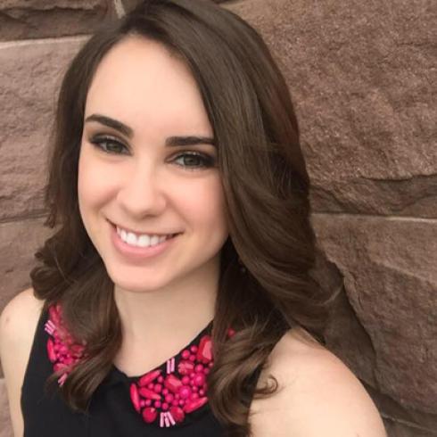 Smiling woman with dark hair, wearing a black top with red accents. This alt text was added with Al; accuracy may vary.