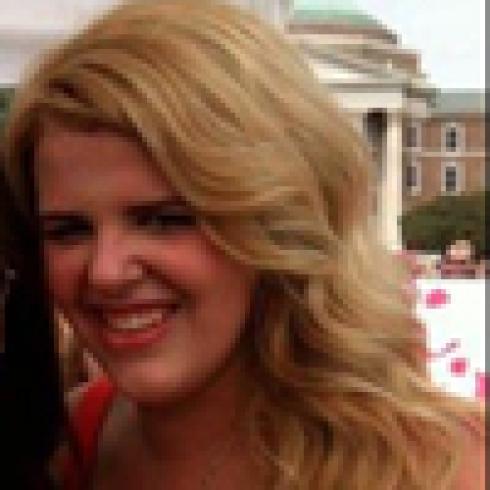 Smiling person in outdoor setting, wearing glasses and a beanie. This alt text was added with Al; accuracy may vary.