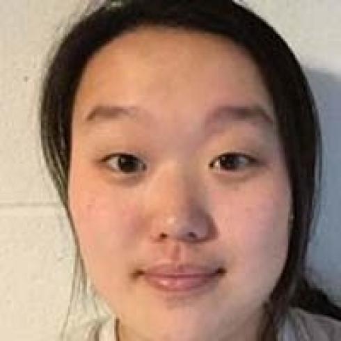 Smiling person with long dark hair, wearing a light-colored shirt indoors. This alt text was added with Al; accuracy may vary.