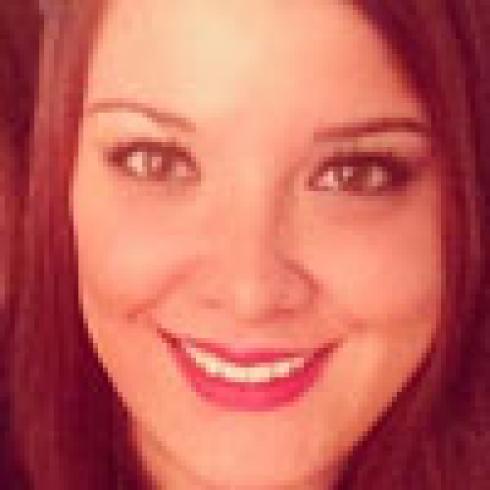 Smiling person with reddish-brown hair, close-up. This alt text was added with Al; accuracy may vary.