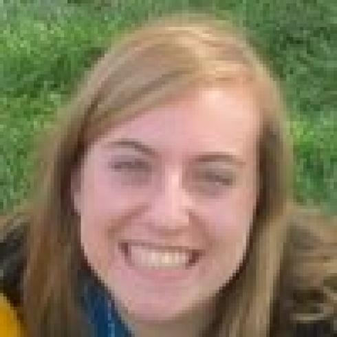 Smiling person with blonde hair in a grassy setting. This alt text was added with Al; accuracy may vary.