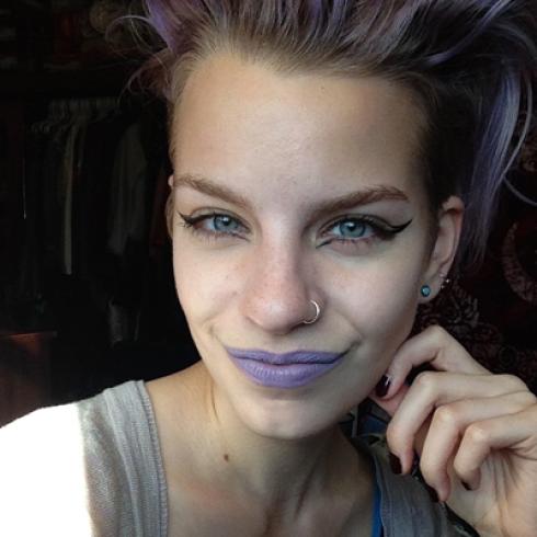 Smiling woman by a pond in a striped shirt, greenery around. This alt text was added with Al; accuracy may vary.