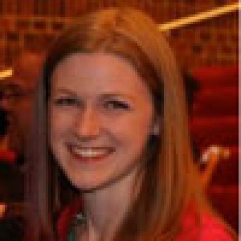 Smiling person with long brown hair, green blurred background. This alt text was added with Al; accuracy may vary.