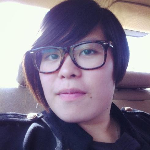 Smiling person with short hair and glasses, seated indoors. This alt text was added with Al; accuracy may vary.