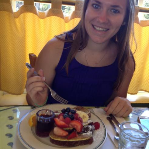 1. Woman smiling with grassy background.
2. Person smiling outdoors with bushy background.
3. Smiling woman wearing green sweater with scarf.
4. Woman smiling outside on sunny day.
5. Woman enjoying breakfast with fruit and jam. This alt text was added with Al; accuracy may vary.