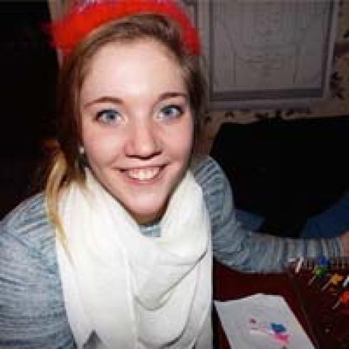 Group of five friends smiling inside a dimly lit room. This alt text was added with Al; accuracy may vary.