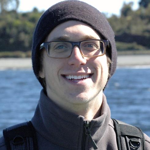 Young man smiling against a plain white background. This alt text was added with Al; accuracy may vary.
