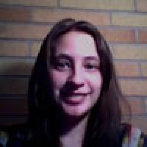 Smiling woman with a toucan on her shoulder. This alt text was added with Al; accuracy may vary.