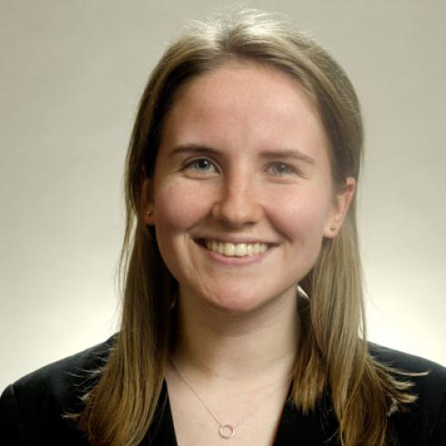 Young woman smiling, wearing a denim jacket against a gray background. This alt text was added with Al; accuracy may vary.