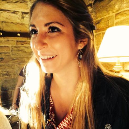 Smiling woman with long hair in a warmly lit room. This alt text was added with Al; accuracy may vary.