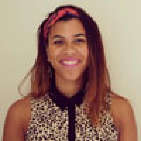 Person smiling, holding a pink rose. This alt text was added with Al; accuracy may vary.