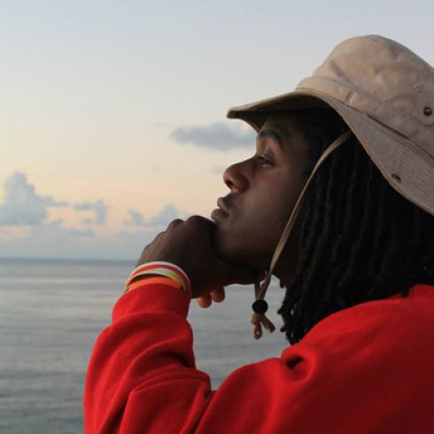 A person in profile, gazing at the ocean at sunset. This alt text was added with Al; accuracy may vary.