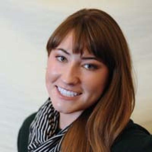 Smiling woman with wavy hair by a tree. This alt text was added with Al; accuracy may vary.