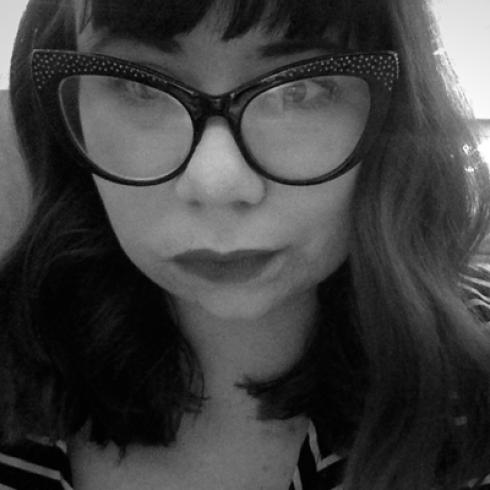 Woman in glasses and striped shirt, monochrome photo. This alt text was added with Al; accuracy may vary.