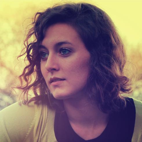 Young woman smiling outdoors, wearing a dark tank top. This alt text was added with Al; accuracy may vary.