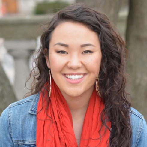 Smiling person with long hair, wearing a necklace, soft focus. This alt text was added with Al; accuracy may vary.