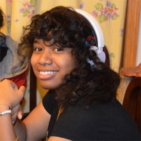 Smiling woman with light pink hair, glasses, wearing a denim shirt. This alt text was added with Al; accuracy may vary.