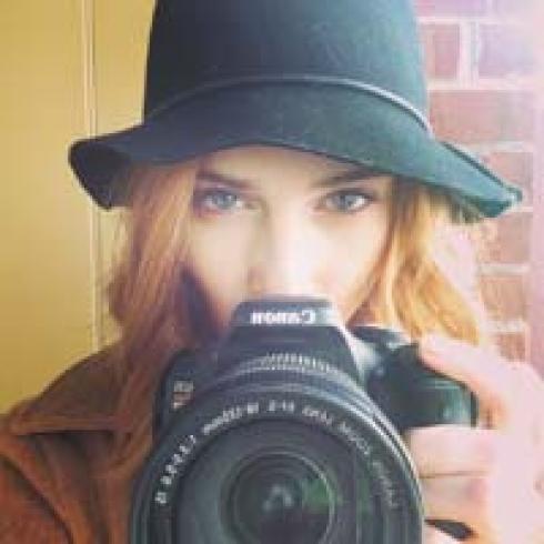 1. Woman smiling, seated outdoors on a wooden chair.
2. Woman in hat holding camera, looking directly. This alt text was added with Al; accuracy may vary.