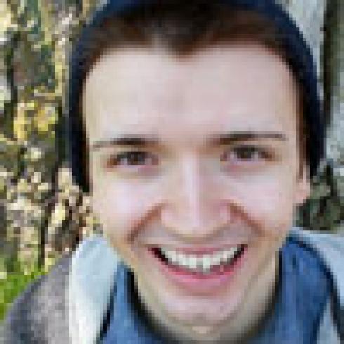 Smiling person with trees in the background. This alt text was added with Al; accuracy may vary.