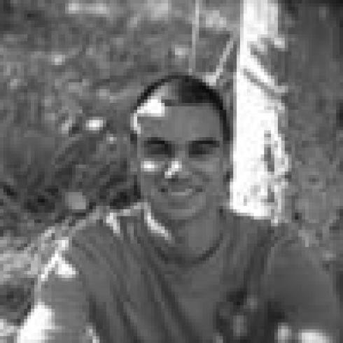 Person smiling outdoors in black and white. This alt text was added with Al; accuracy may vary.