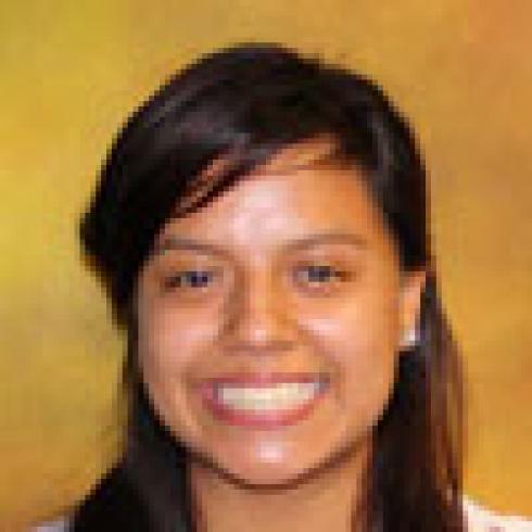 Smiling person with a yellow-orange background. This alt text was added with Al; accuracy may vary.