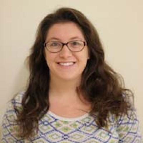 Smiling woman with long hair, glasses, wearing a patterned shirt. This alt text was added with Al; accuracy may vary.