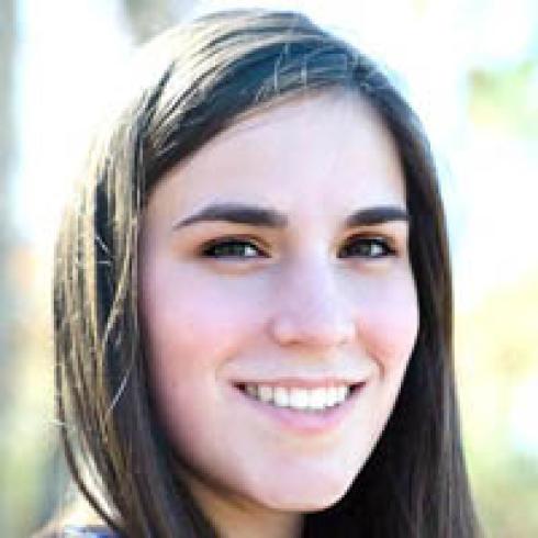 Young person with dark, curly hair wearing a polka dot shirt, neutral expression. This alt text was added with Al; accuracy may vary.
