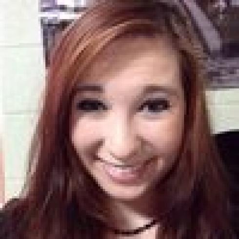 Smiling person with long auburn hair. This alt text was added with Al; accuracy may vary.