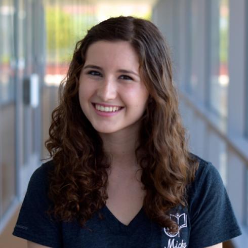 Smiling woman with straight hair sitting outdoors on a bench.

Smiling woman with curly hair in a hallway wearing a black shirt. This alt text was added with Al; accuracy may vary.