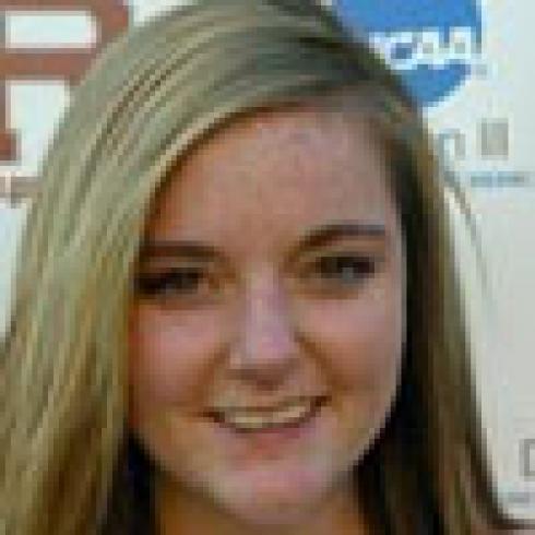 Young person smiling, partially blurred background with logos. This alt text was added with Al; accuracy may vary.